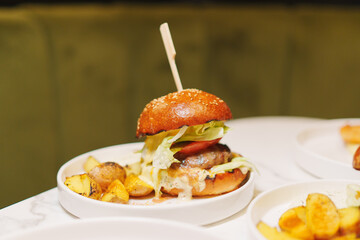 A classic American dish of a hamburger and french fries served on a plate with tableware, a staple food in Western cuisine, made with ingredients like beef, potatoes, and condiments