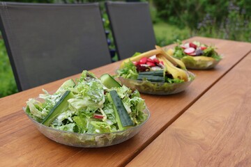 Drei Salate mit frischen, grünen, gesunden Salatblättern und leckeren Zutaten stehen auf dem...