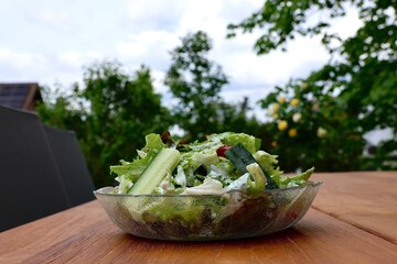 Salat mit Joghurtdressing und bunten Toppings als Garnitur seitlich auf einem Gartentisch im Freien