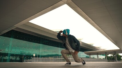 Motion shot of happy hipster practice b boy dance with stylish cloth at building. Dancer enjoy show...