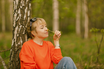 a girl in blue jeans and an orange jumper among birch trees, taken on a cloudy spring day in the village of Shanary in Chuvashia