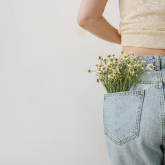 Chamomile daisy flowers bouquet in jeans pocket. Summer fashion, floral creative concept. Close...
