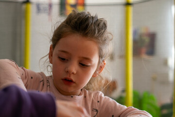 Family interaction: Concentrated girl shares a game with mom in a warm home environment.