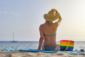 Unrecognizable woman in hat sitting on beach