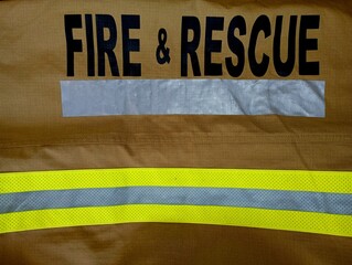The inscription on the combat clothing of the firefighter fire & rescue in black font on a brown background with a reflective yellow stripe below.