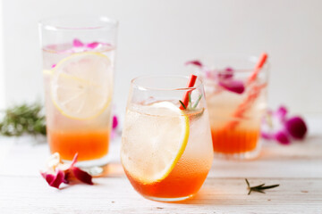 Glass of iced summer soda with lemon and pink orchid flower.