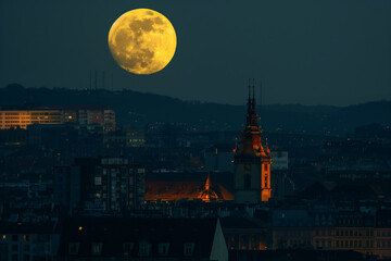 Naklejka premium Huge full moon at night with lights from city view