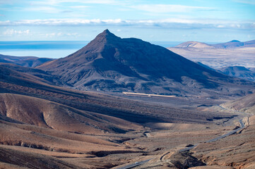 Naklejka premium Panoramic view on colourful remote basal hills and mountains of Massif of Betancuria as seen from observation point, Fuerteventura, Canary islands, Spain