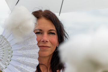 a woman with a white fan and umbrella and a cloud in the foreground