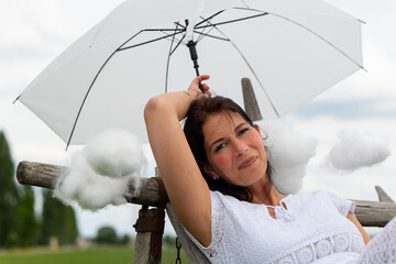 woman is holding a white umbrella and surrounded by cotton clouds