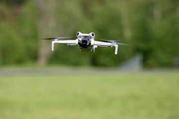 Dron w locie, w powietrzu na tle zielonych drzew. © Stanisław Błachowicz