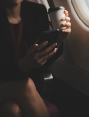 Blonde female tourist checking incoming notification on smartphone sitting on seat of airplane with...