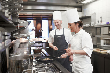 Teamwork, meat and chef with frying pan in kitchen for catering service, fine dining or prepare...