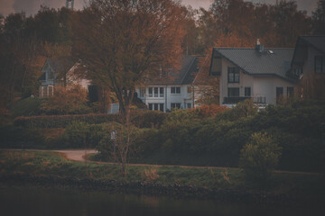 photograph of houses from the water side in autumn style