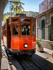 The iconic Tramvia de Sóller tram arrives at Port de Sóller station, ready to transport tourists to explore the charming town, embodying the timeless allure of vintage transportation in Mallorca.