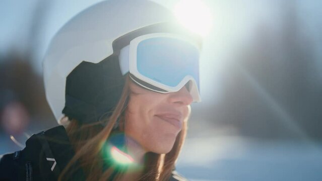 Close-up portrait of woman snowboarder skyer in ski helmet and glasses in mountains, side view. Girl wearing in ski clothes in winter resort. Enjoy healthy active rest, snowboarding lifestyle.
