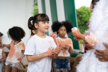 Young Asian girl smiles and diverse friends have fun hands painted in colorful paint. Education concept