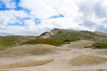 Gras bewachsene Dünen und Sanddünen mit leicht bewölktem, blauen Himmel im Naturschutzgebiet von Noordholland im  Molecaten Park Noordduinen