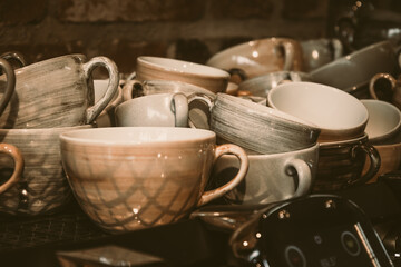 Stacked glossy brown and gray earthenware coffee cups front of a stone wall