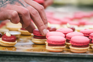 Confectioner's hands finishing pink macarons