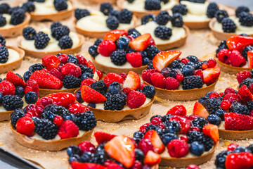 Tartlets with raspberries, blackberries, strawberries, currants, blueberries on a tray