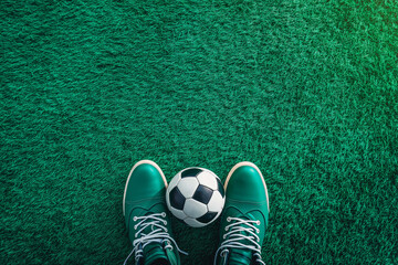 Soccer football background. Soccer ball and pair of football sports shoes on artificial turf soccer field. Top view