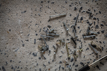 Screw, nail on concrete texture background. Closeup of screws and nails on cement floor, copy space.