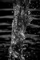 Gouttelettes en suspension d'un jet d'eau d'une fontaine - Arrière plan sombre noir et blanc