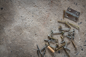 Screw, nail on concrete texture background. Closeup of screws and nails on cement floor, copy space.