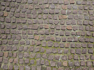 Footpath paved with brown stone paving tiles, fragment top view