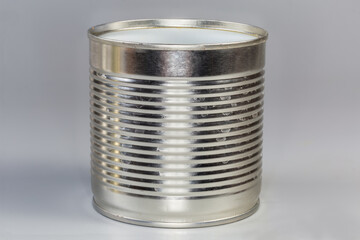 Open empty tin can on a gray background, side view