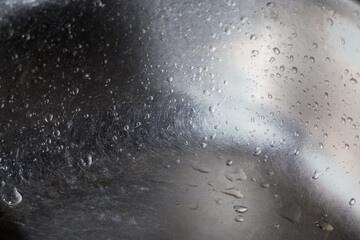 Stainless steel kitchen sink covered with water drops, selective focus