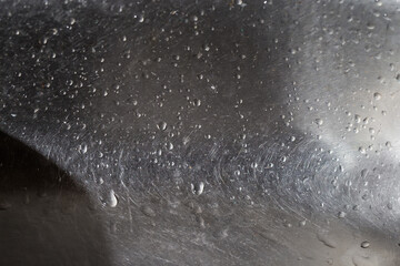 Stainless steel kitchen sink covered with water drops, selective focus