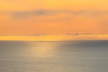 Fototapeta premium Ocean sea background. Sunset over atlantic ocean with yellow sky and clouds.