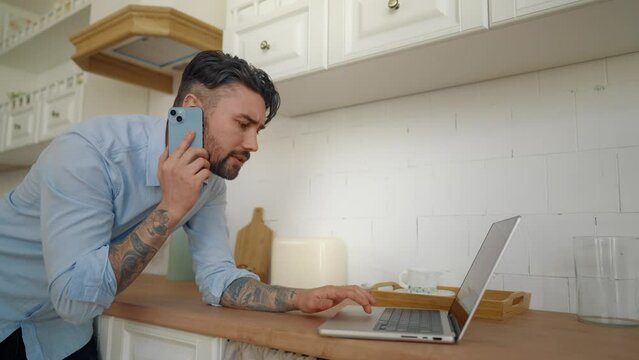 Busy man talking on cell phone at home. Businessman salesman pacing back and forth at home checking information with laptop in his hands, call with clients. Online remote work, home workplace concept.