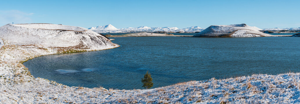 Panorama view on a snow covered landscape with lake Myvatn and volcanic explosion craters in autumn, Iceland