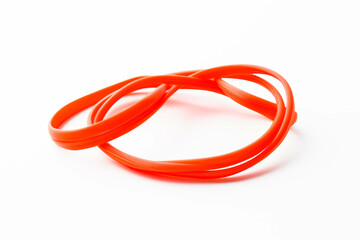 Naklejka premium A bright red rubber band, stretched and twisted into an interesting shape, resting on a stark white background.