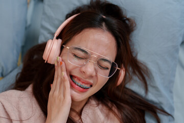Person in pink, glasses, laughing, with headphones, exemplifies leisure joy, relaxed pose on soft...