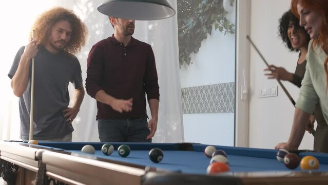 Happy woman pocketing pool ball with successful shot in game room