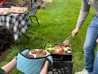 Cropped shot of men grilling vegetables and burgers on a garden bbq grill