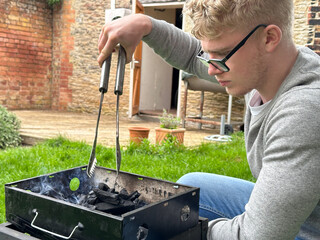 Man starting grill pit fire for backyard barbecue
