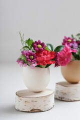 Florist at work: woman shows how to make simple Easter decoration with egg shell and various flowers. Step by step, tutorial.