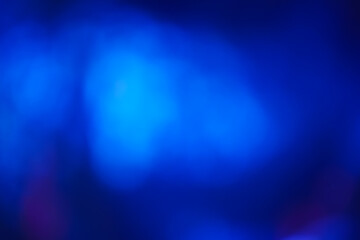 Abstract image with soft undefined shapes of blue color and blurry lights like those of a music concert stage. Dark background.