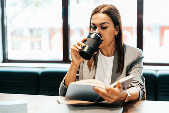 woman working in an office drinking coffee from a thermos flask