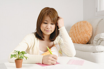 直筆で手紙を書く思案顔の若い日本人女性