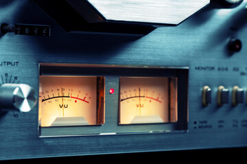 Arrow indicators of the recording level on a reel-to-reel tape recorder. Stereo VU meter background.