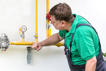 An adult European homeowner records readings from his domestic gas meters.
