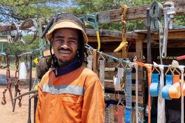 african street vendor selling hardware on the side of the road, wearing orange workwear and dreadlocks braids