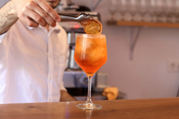 Unrecognizable waiter preparing a fresh cocktail by putting a slice of orange