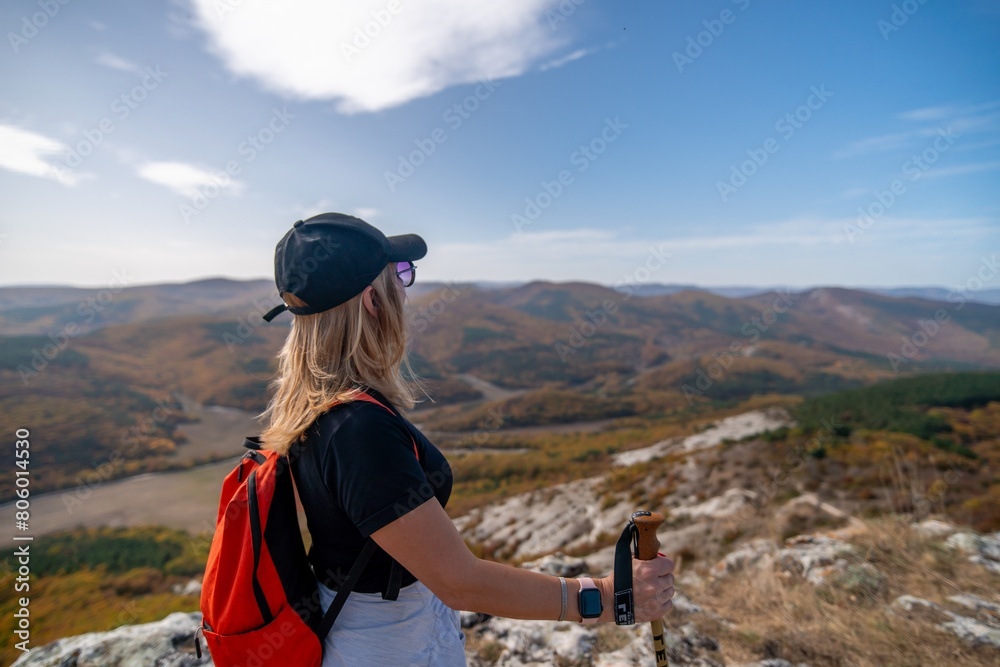 Wall mural woman on mountain peak looking in beautiful mountain valley in autumn. Landscape with sporty young woman, blu sky in fall. Hiking. Nature